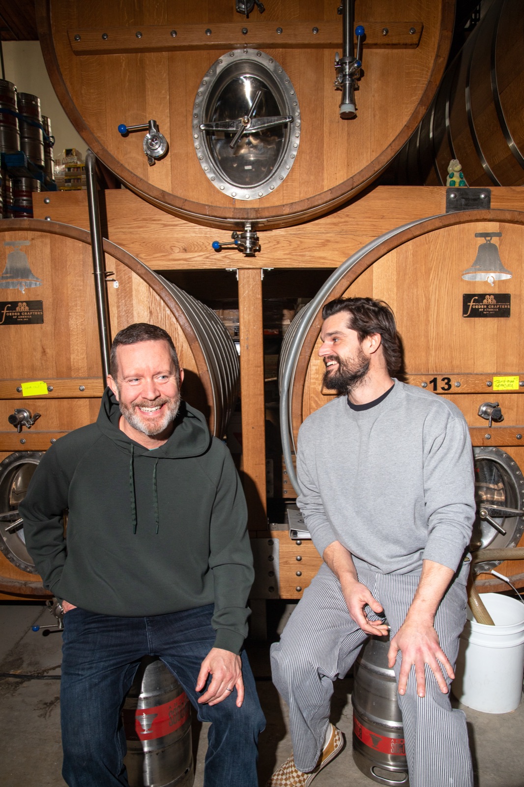 Co-founders Mike Clark and Luke Pestl sitting on kegs in front of oak foeders
